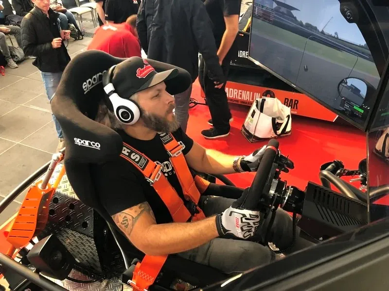 Tätowierter Fahrer mit Kopfhörern im Rennsimulator