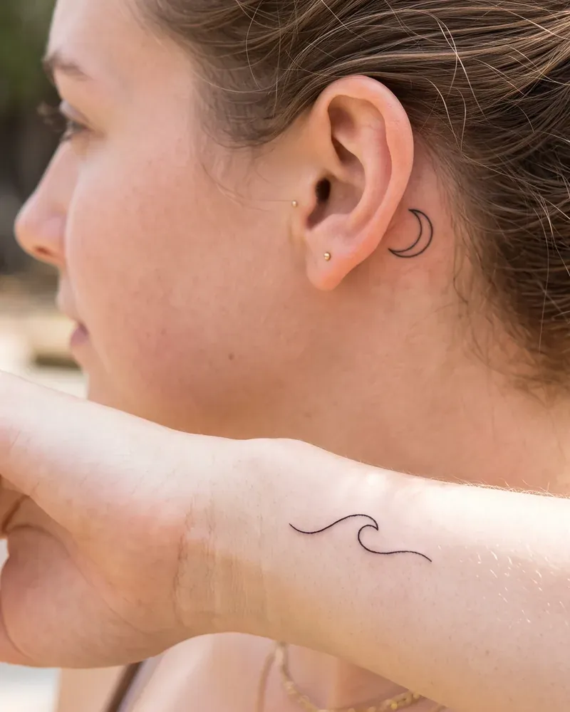 Minimalismus Tattoo: Kleine Symbole hinter dem Ohr und am Handgelenk.